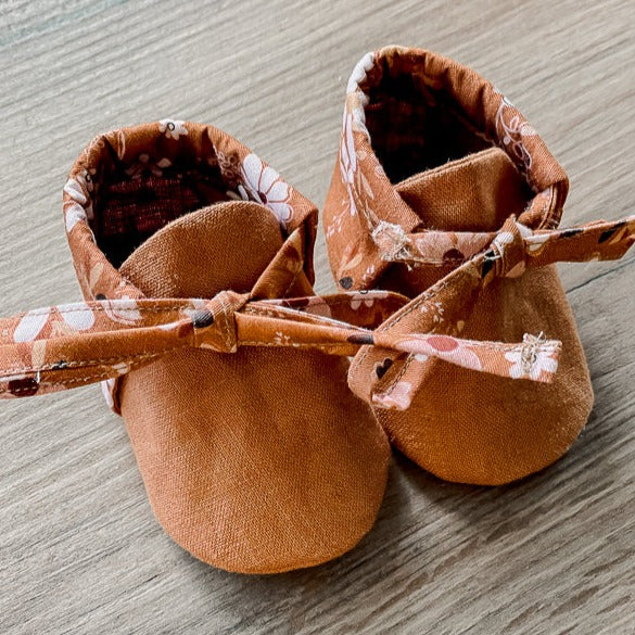 a Pair of Brown Linen baby booties with floral backing 