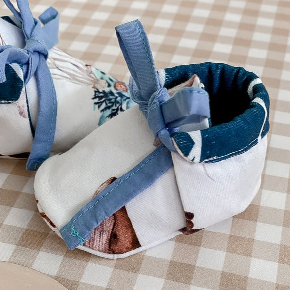 a Pair of baby booties made from Snuggly Jacks Ocean Jersey Fabric on a baby bassing with an announcement disc