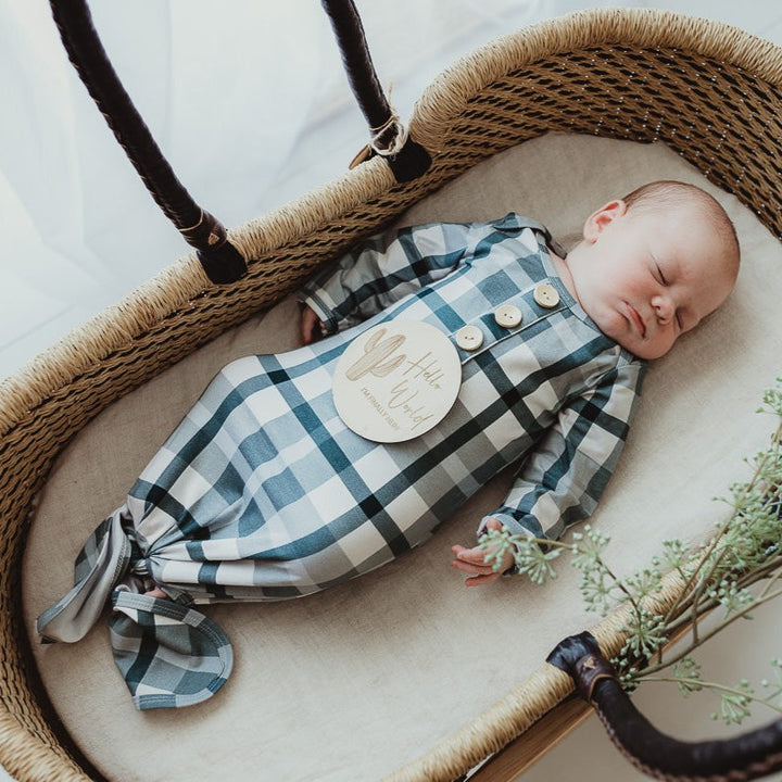 Sweet little dude in a blue knotted gown sleeping in a moses basket with a cactus announcement disc