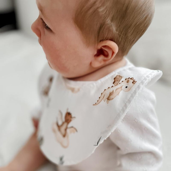 Baby wearing a Mystique print organic cotton bib with adjustable snap closure, featuring whimsical dragons and absorbent microfiber backing.