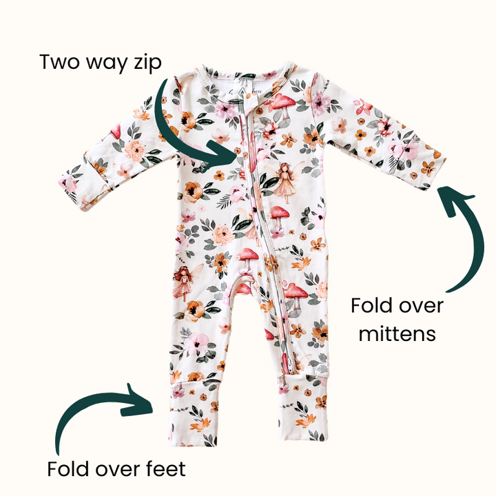 Fairies and floral print organic cotton onesie showcasing practical features like a two-way zip, fold-over mittens, and fold-over feet.