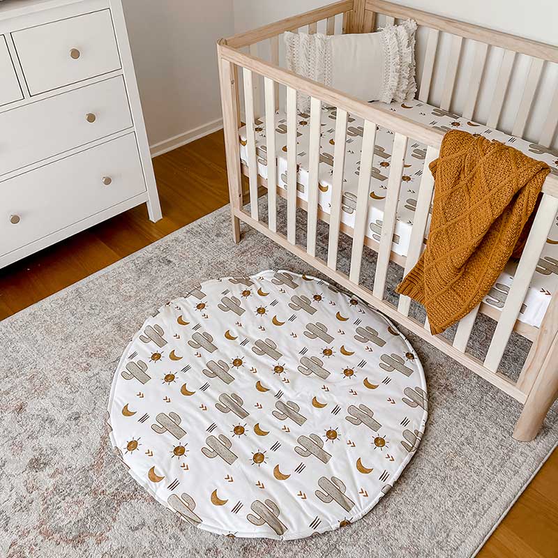 Snuggly Jacks Nursery with a Crib featuring Arizona fitted crib sheet and a round baby tummy time mat on the ground. 