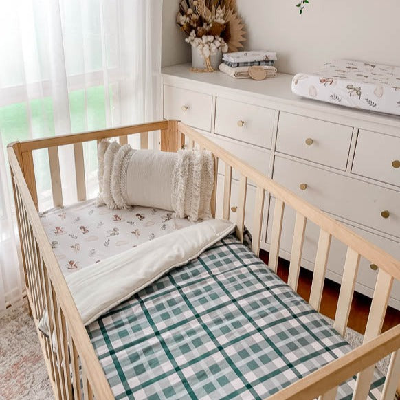 Pine crib set with a dragon print sheet and a plaid cotton crib quilt.