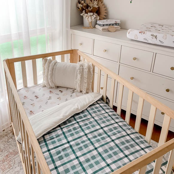 Modern nursery set up with blue plaid playmat, blue plaid quilt and a dragon print change pad cover on a white chest of draws