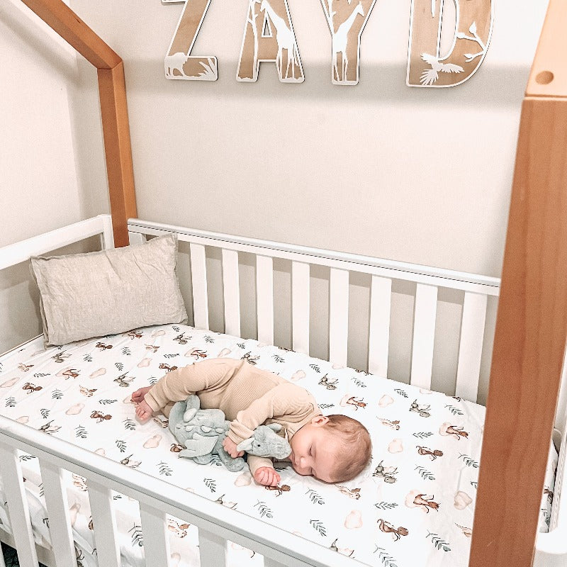 A cute a frame crib, fitted crib sheet from snuggly jacks demonstrating a dragon print with alternating leaves and clouds.