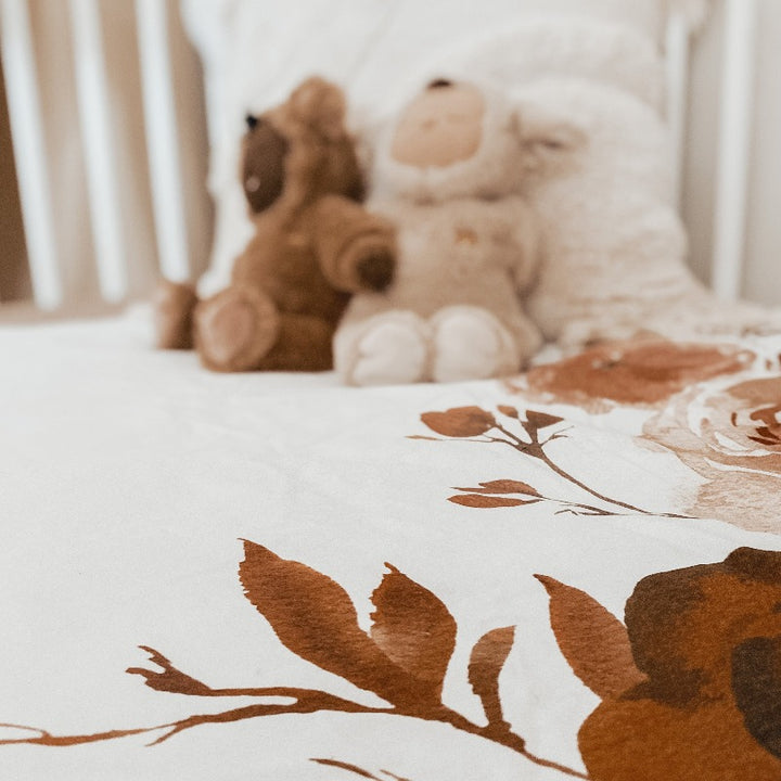 Low angel of two plush toys sitting on a quilt in a white pine cot