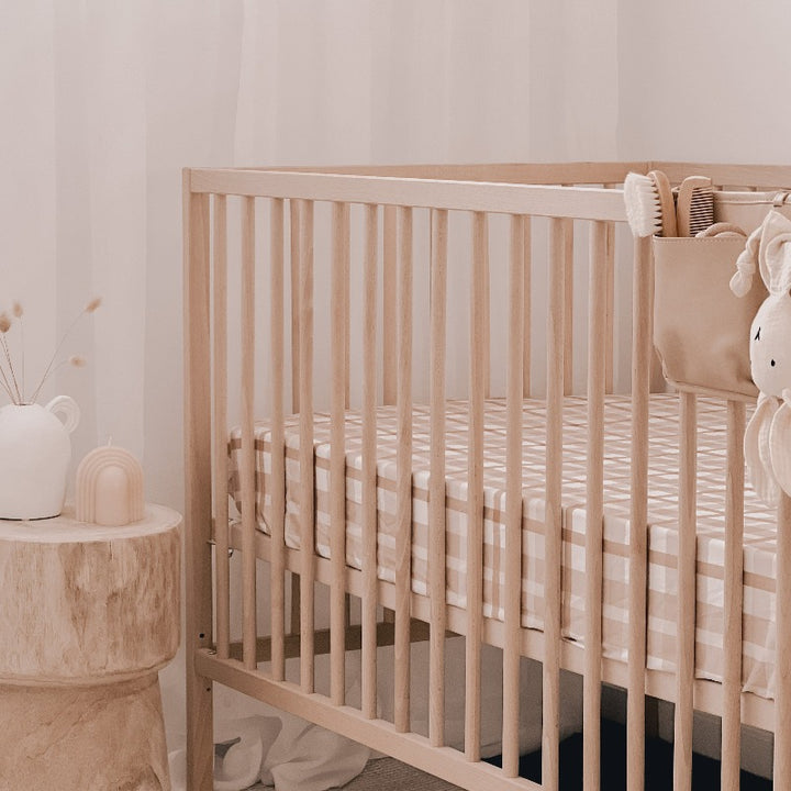 Adorable cot with a plaid fitted cotton sheet in a well designed nursery