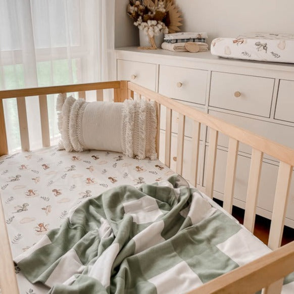 Modern nursery designed using dragon prints on a fitted crib sheet, bassinet cover and burp cloths.