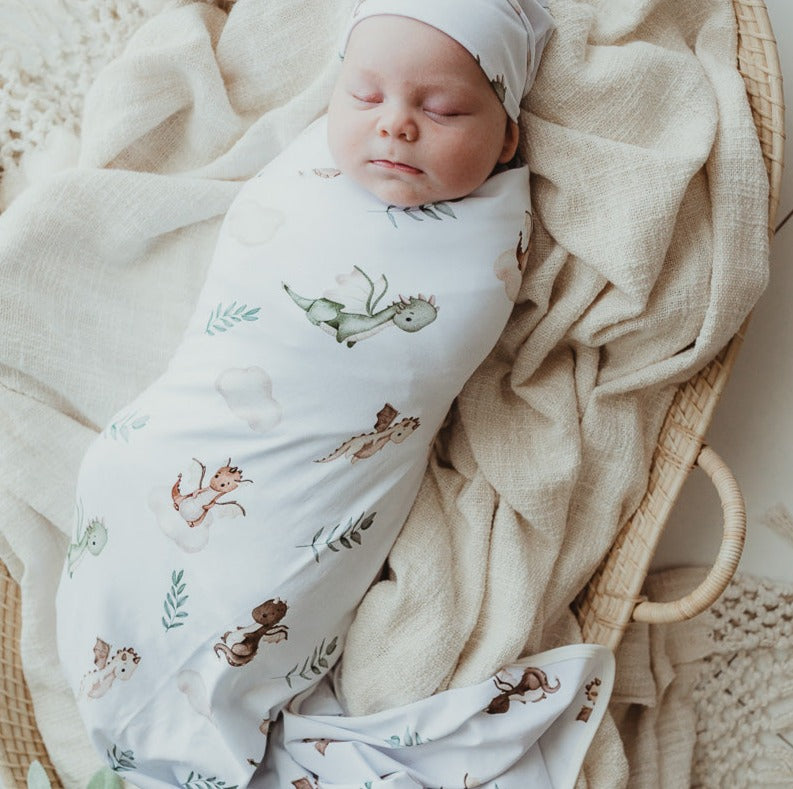 Adorable baby laying on top of a cotton wrap set inside a rattan bassinet