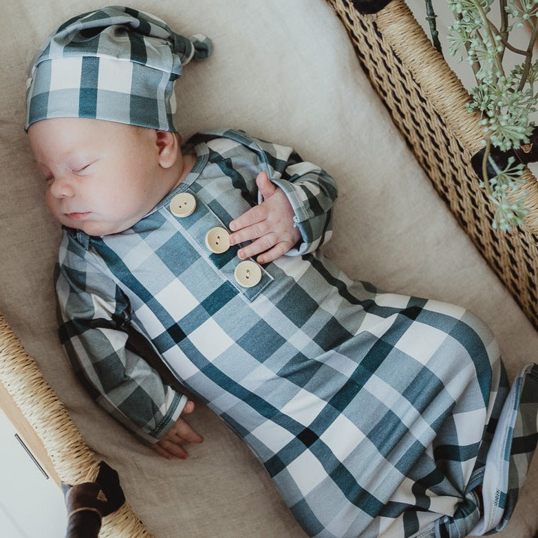 Baby wearing a knotted gown and a matching blue plaid beanie