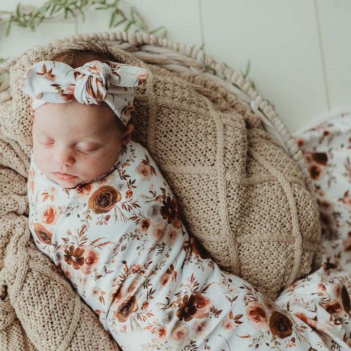 Baby wearing a willow top knot and swaddled in a snuggly jacks stretch wrap