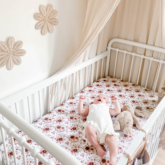 An adorable baby laying beside a stuffed bunny both in a cot using the WIllow fitted sheet from snuggly jacks australia