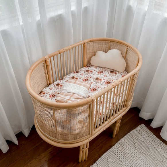 Rattan Bassinet set with a selection of snuggly jacks cotton products in warm browns and soft pinks.