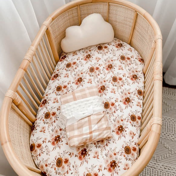 Rattan Bassinet set with a selection of snuggly jacks cotton products in warm browns and soft pinks.
