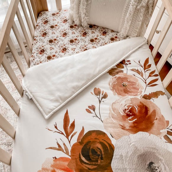 Over head shot of a pine cot depicting a floral cot quit made from 100% cotton