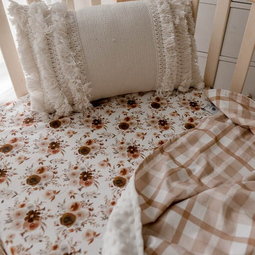 Close up of the willow fitted cot sheet in a pine cot with an earthy plaid dimple dot minky pram blanket