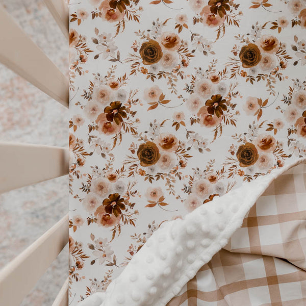 Snuggly Jacks Australia willow Floral fitted cot sheet shown in a pine cot with an earthy plaid dimple dot minky blanket draped over one corner.