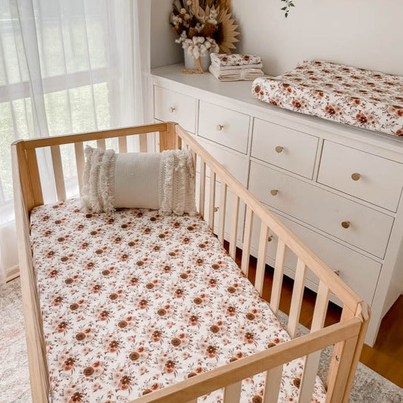 A nursery with fitted crib sheet, burp cloths and a change pad cover all in the new willow floral print from snuggly jacks Canada.