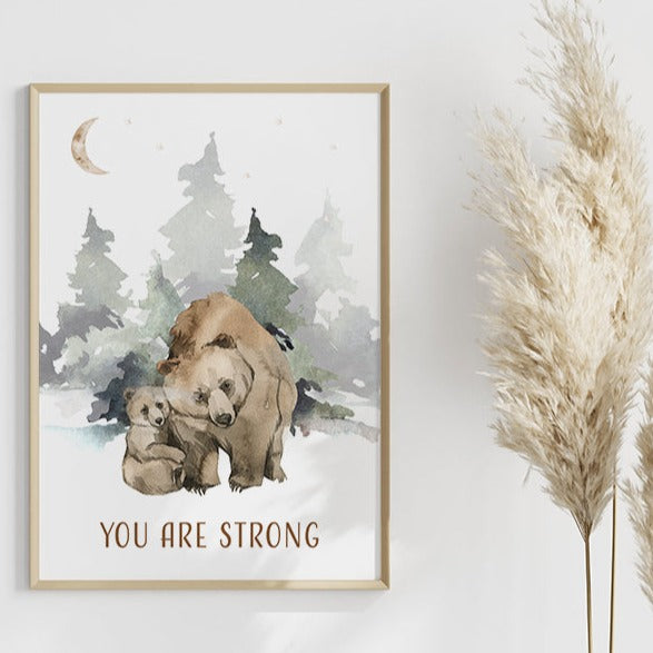 Wooden framed picture of a bear and its cub in the forest hanging on a wall with padanus grass next to it. 