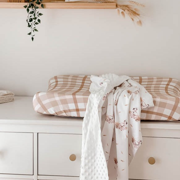 White minky pram blanket laying on top of a change mat 