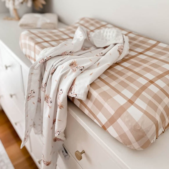 Swan printed dimple dot minky draped over a change pad with a cotton cover sitting on a white chest of draws.
